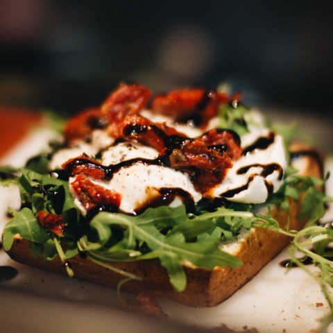 Open Italian meatball sandwich with mozzarella, roasted tomato, arugula and balsamic syrup