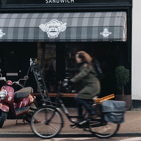 Gevel van Meat The Balls aan de Kinkerstraat 142 in Amsterdam Oud-West, met de grijs-witte luifel en bordeaux scooter ervoor
