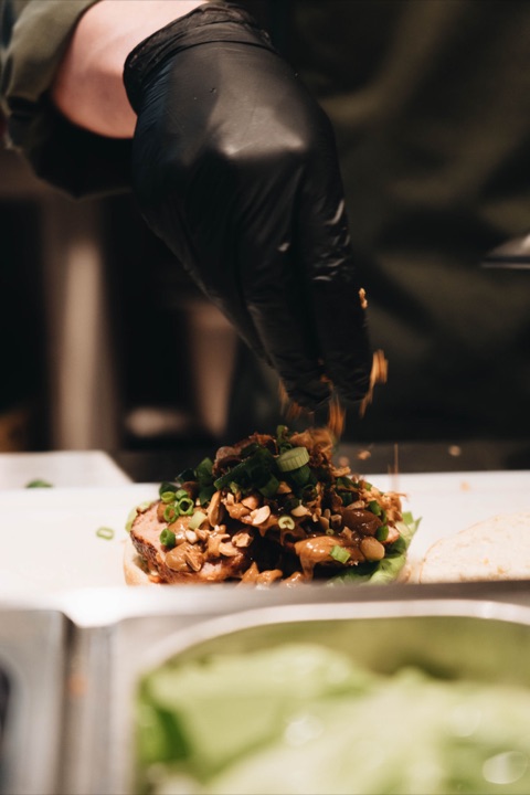 Close-up: peanuts and spring onion sprinkled over an Indonesian meatball sandwich