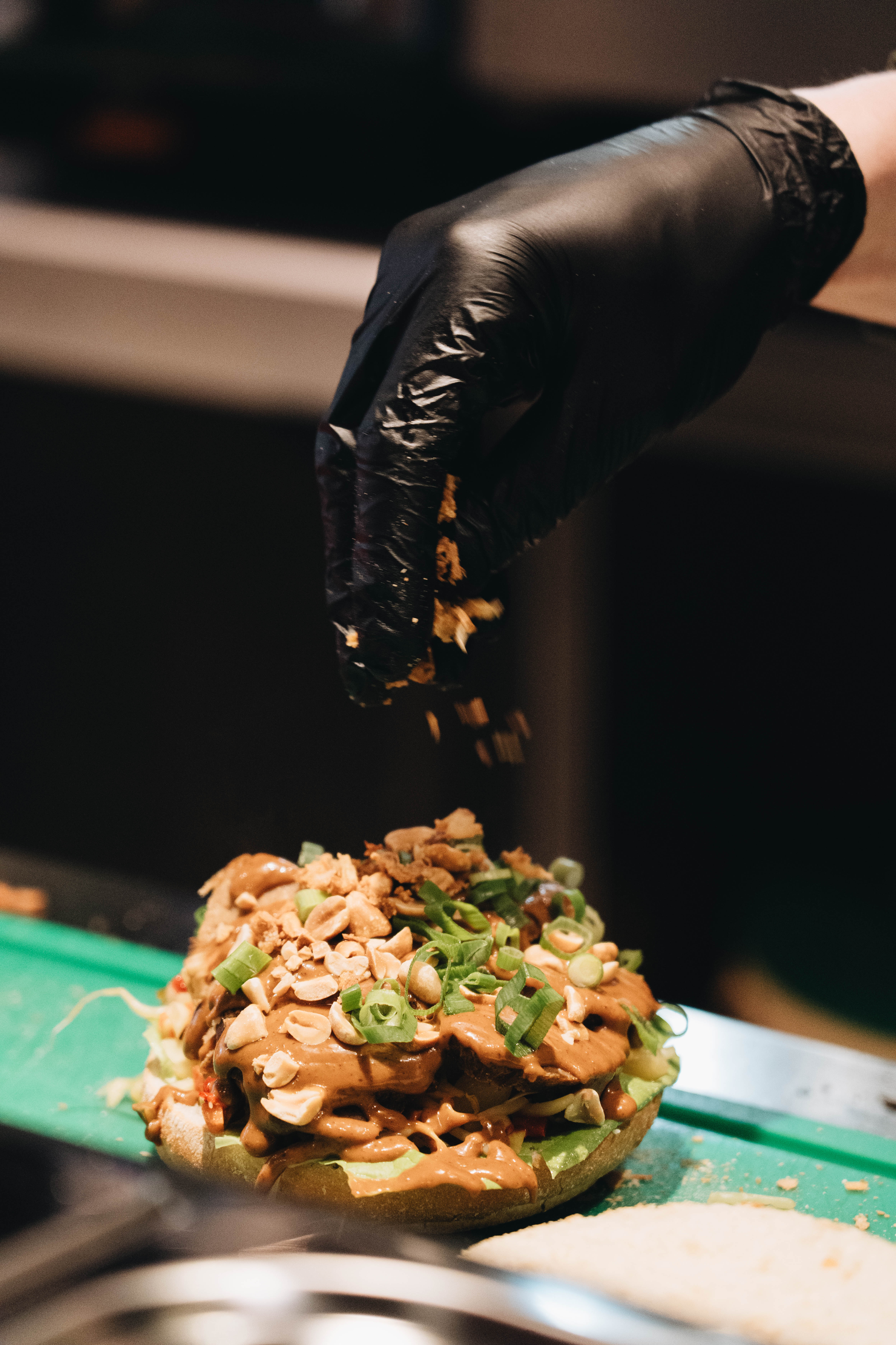 Verse toppings worden over de gehaktbal gestrooid in de open keuken aan de Kinkerstraat