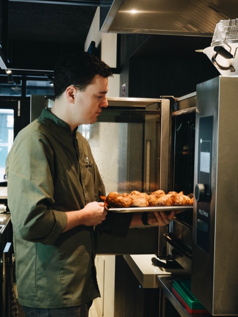 Kok haalt vers gebakken gehaktballen uit de oven in onze open keuken aan de Kinkerstraat